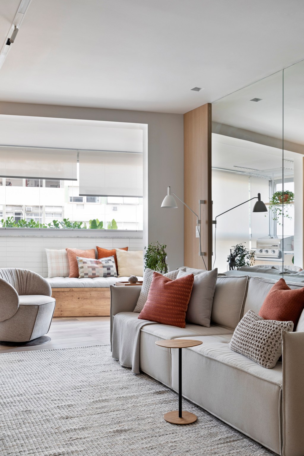 Apartamento de 70 m² parece maior com décor em tons neutros. Projeto de Fabiano Ravaglia. Na foto, sala de estar com sofá e parede espelhada.