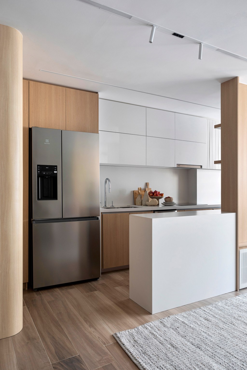 Apartamento de 70 m² parece maior com décor em tons neutros. Projeto de Fabiano Ravaglia. Na foto, sala integrada com cozinha e balcão branco.