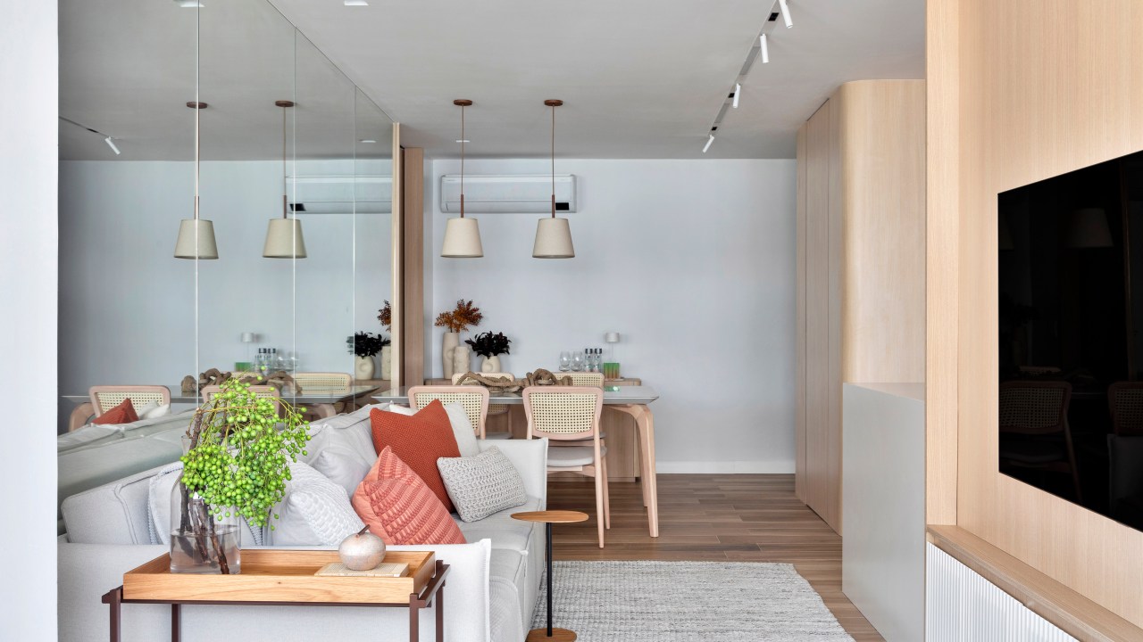 Apartamento de 70 m² parece maior com décor em tons neutros. Projeto de Fabiano Ravaglia. Na foto, sala de estar e jantar com parede espelhada.