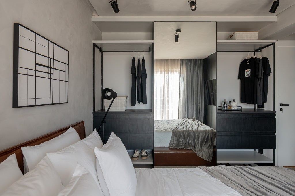 Cores escuras criam sobriedade neste apartamento de 100 m². Projeto de Romário Rodrigues. Na foto, quarto com armário aberto e espelho.