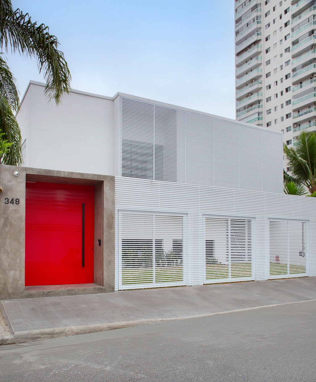 Paixão pelo automobilismo norteia o projeto desta casa de praia. Projeto de Gabriel Fernandes. Na foto, fachada com porta vermelha.