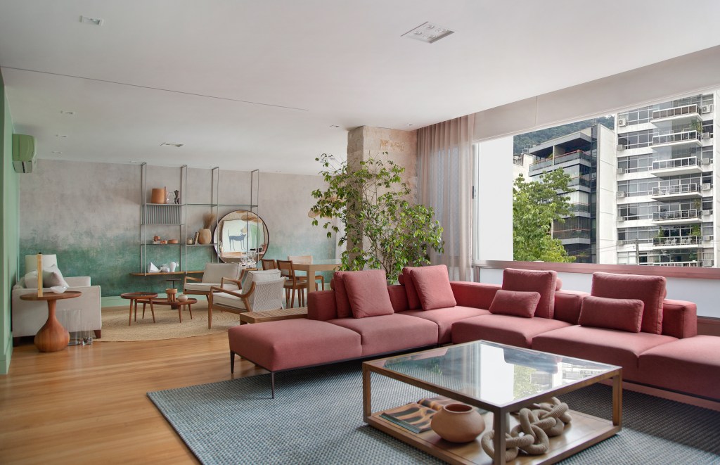Papel de parede com efeito degradê envelhecido é destaque deste apê. Projeto de Manoela Fleck. Na foto, sala de estar e jantar com mesa, estante e sofá.