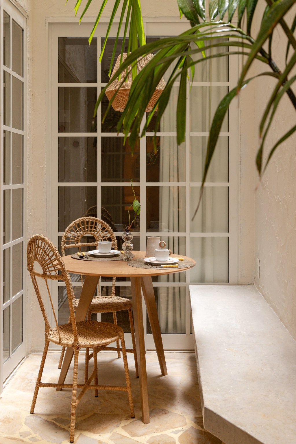 Reforma transforma imóvel de 45 m² em refúgio tropical. Projeto de Tauari Arquitetura. Na foto, pátio com mesa de refeições e banco.