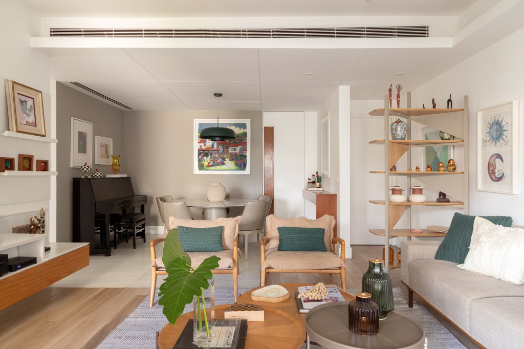 Sem quebra-quebra, apê de 150 m² aposta em tons suaves e cozinha verde. Projeto de Ana Cano. Na foto, sala de estar e jantar, estante, piano e sofá.