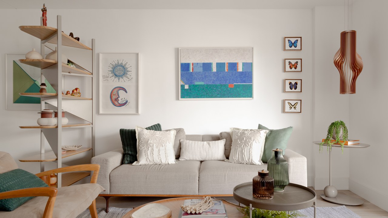 Sem quebra-quebra, apê de 150 m² aposta em tons suaves e cozinha verde. Projeto de Ana Cano. Na foto, sala de estar com sofá, quadro e luminária.
