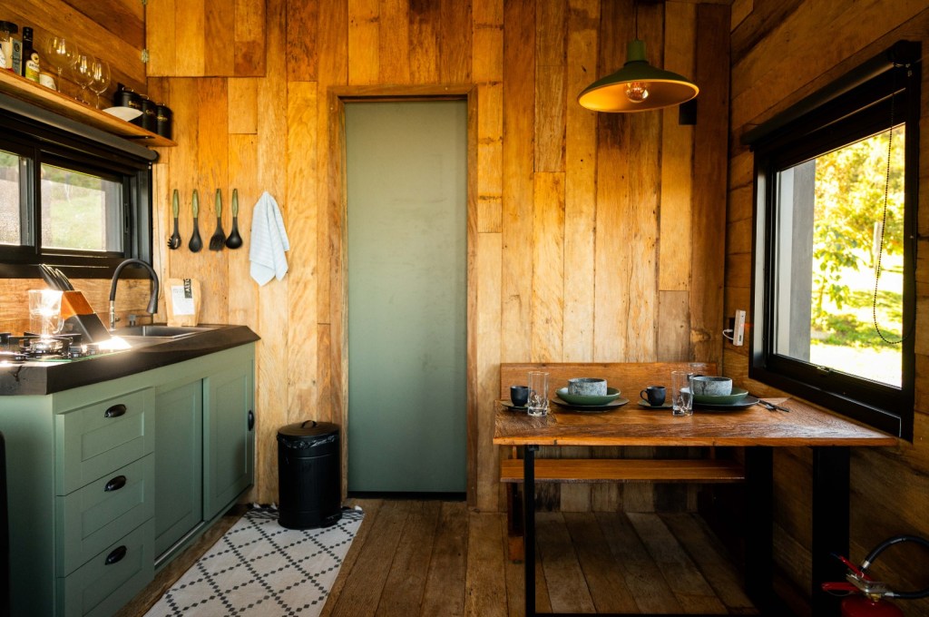 Tiny house sustentável fica a 1500 m de altitude na região serrana de SP. Projeto de Ricardo Delgallo. Na foto, cozinha e sala de jantar rústica.