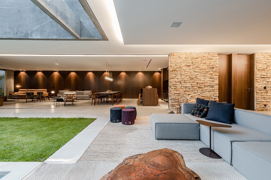 Tons escuros e grandes aberturas criam sofisticação em casa de 430 m². Projeto de Aline Borges. Na foto, sala integrada com jardim com piscina.