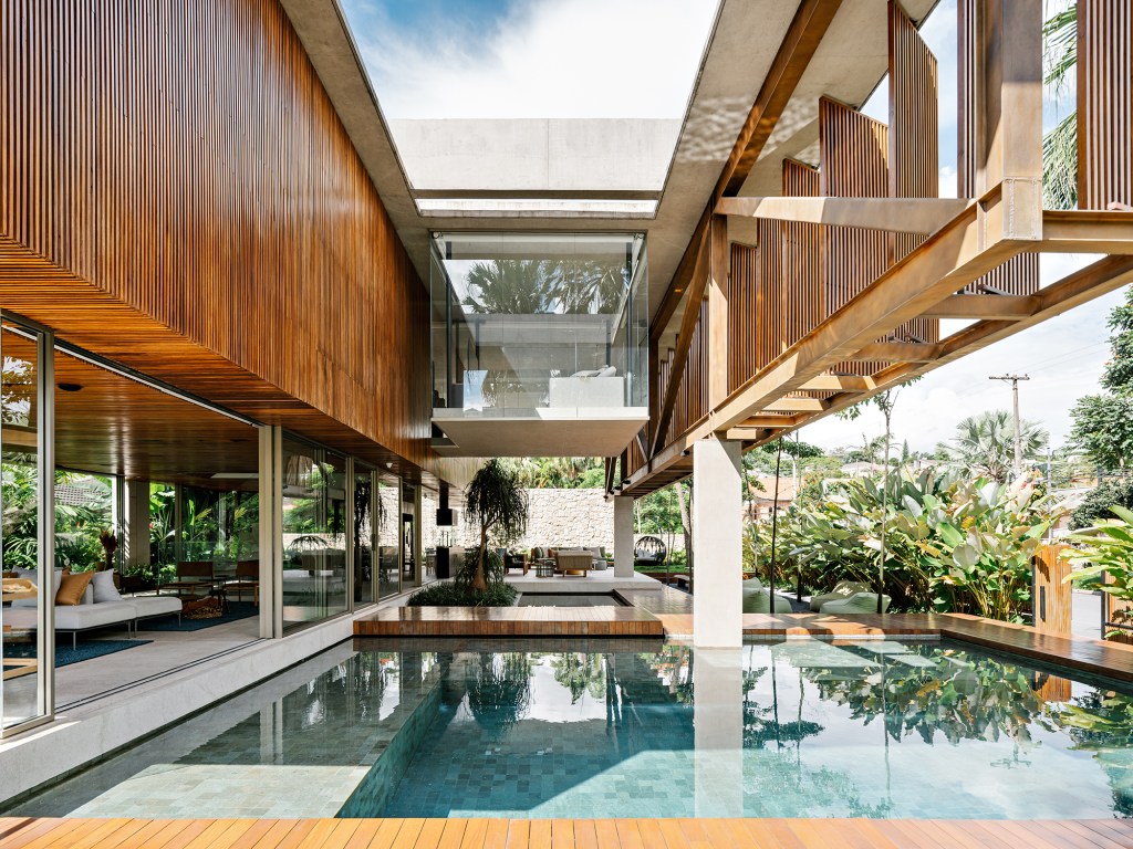 Treliça metálica de 22 m parece flutuar em frente à esta casa de 1275 m². Projeto de FGMF. Na foto, varanda com piscina e treliça de madeira.